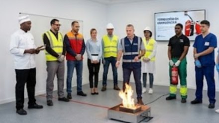 Grupo de trabajadores en practicas de extincion de incendios con un extintor